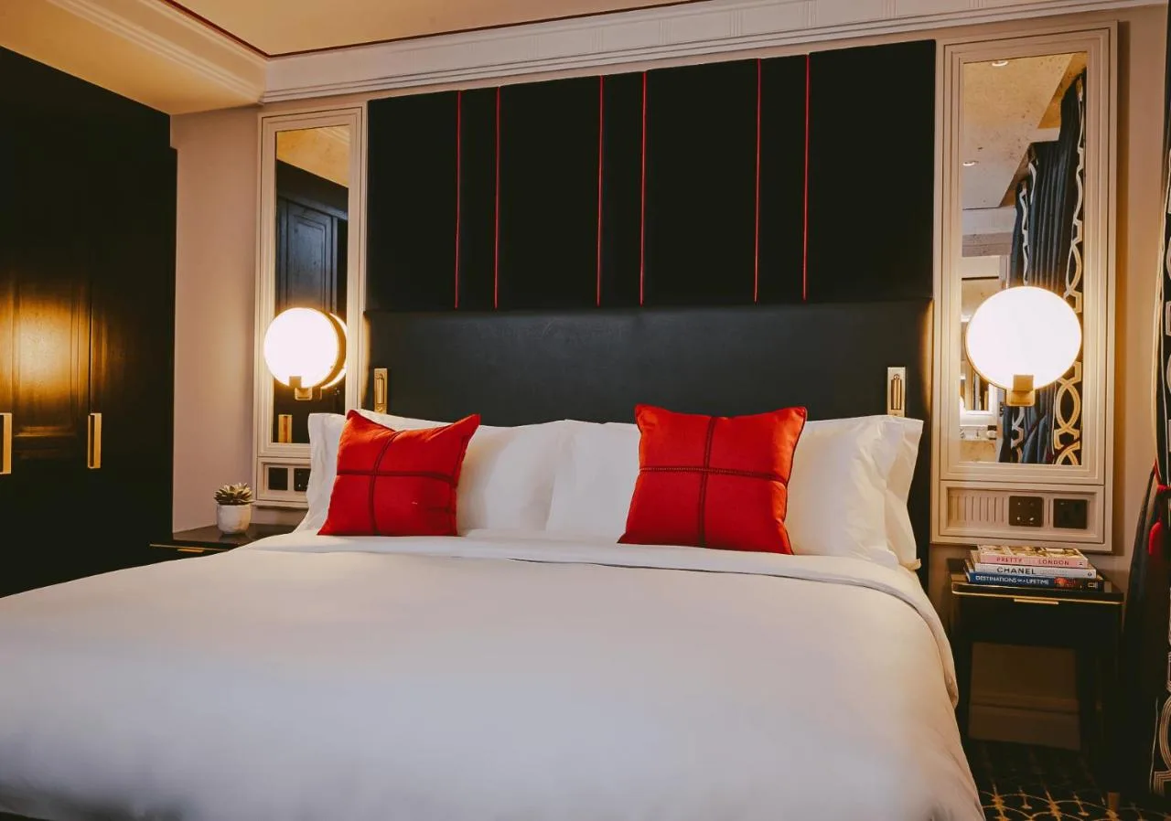 A bedroom with a large white bed with red pillows at The Mayfair Townhouse in London